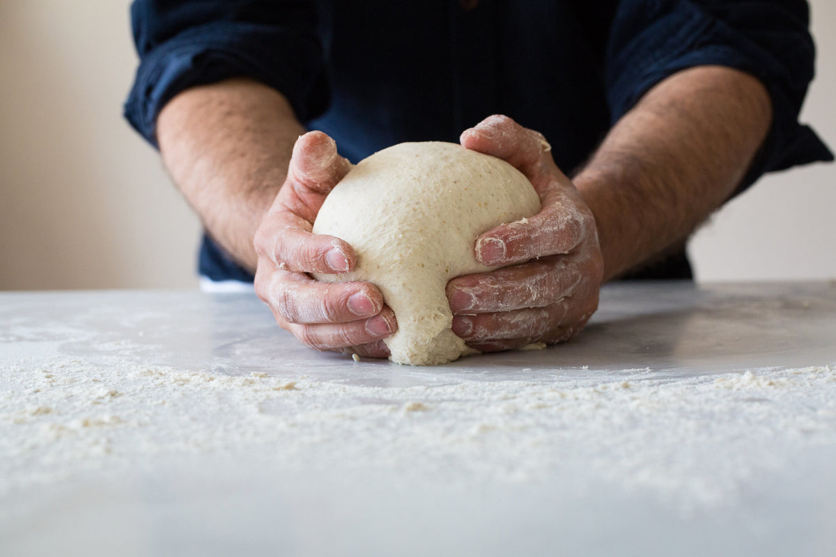 Person kneading dough on a floured surface