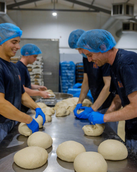 Happy bakers moulding dough by hand.