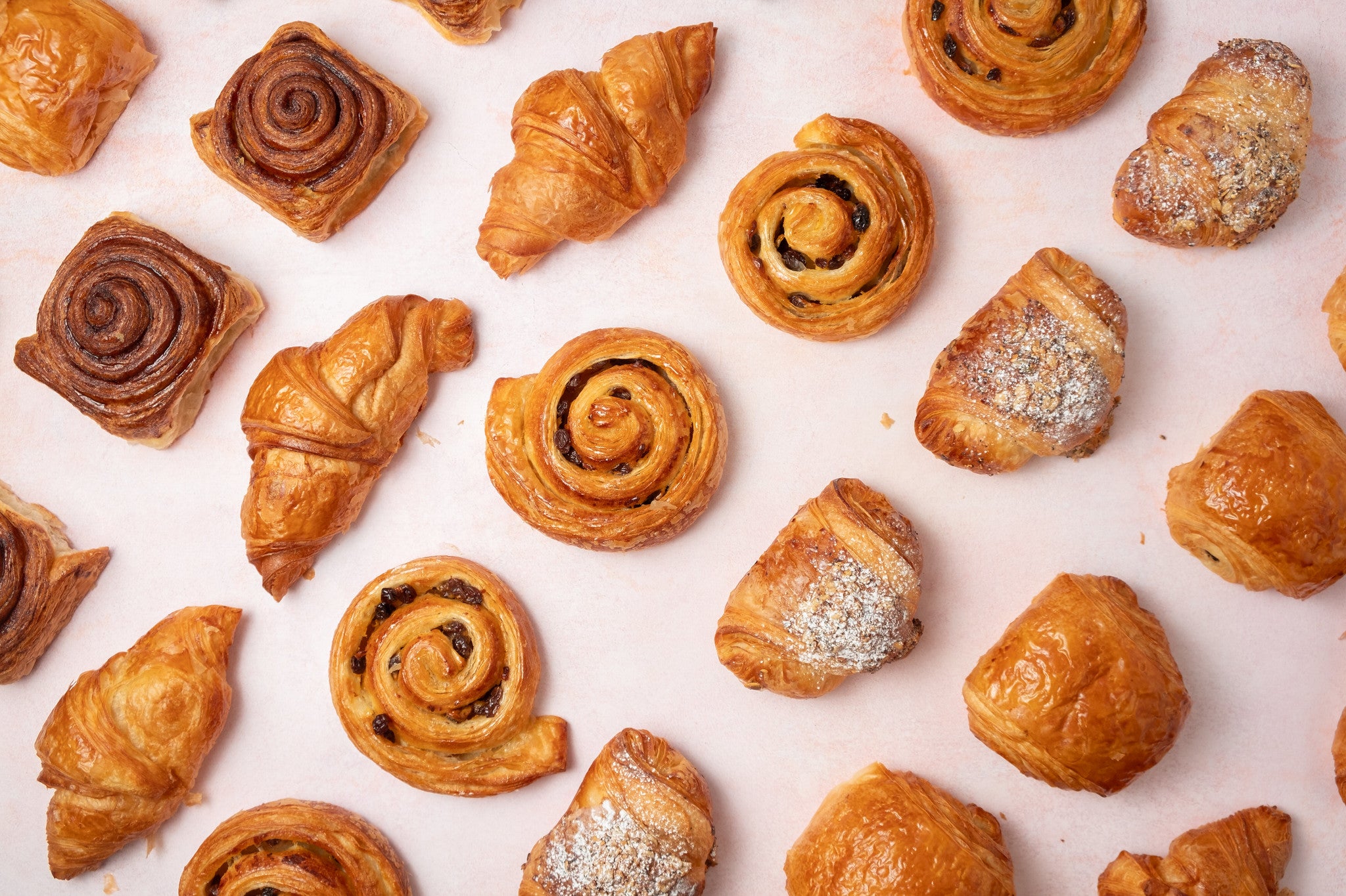Assorted pastries including croissants and cinnamon rolls on a light background